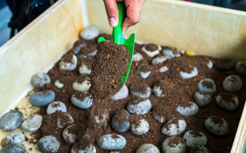 adding soil and drainage material to garden planter